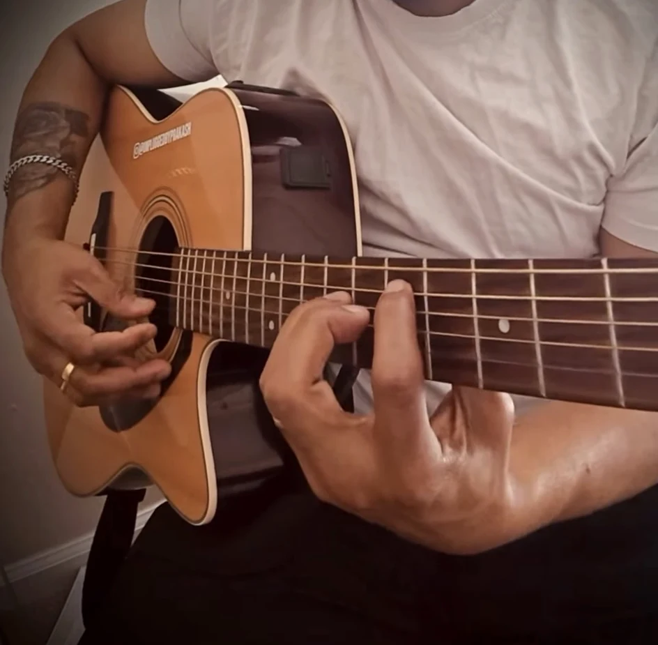 Close-up of Prakash playing acoustic guitar